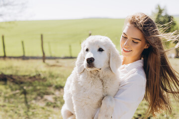 Woman Joyfully Holding Adorable Fluffy Puppy in Sunlit Countryside, Capturing Moments of Happiness and Connection