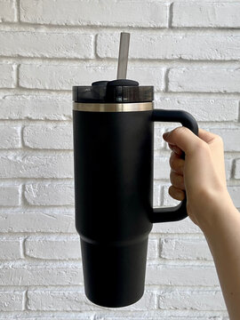 Hand Holding Black Insulated Tumbler with Straw &ndash; Reusable, Eco-friendly, and Portable Beverage Container for Everyday Hydration