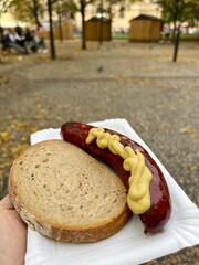 Octoberfest traditional hot dog topped with mustard and a slice of bread.  Taken outside 