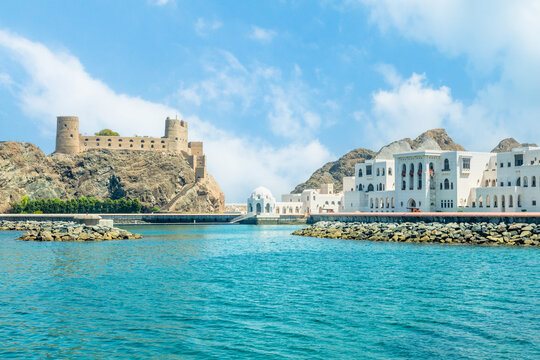 View to the arabian Al Jalali castle standing on the rocks and white royal palace buildings, Muscat, Oman