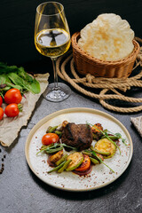 Grilled beef steak with vegetables and herbs, served with wine in a rustic presentation