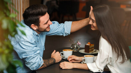 Loving Couple Having Romantic Date In Coffee Shop. Man Touching Girlfriend's Hair Dating In Cafe.