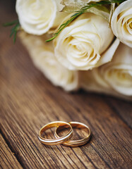 Pair of golden wedding bands on wooden table. Ring for bride and groom.