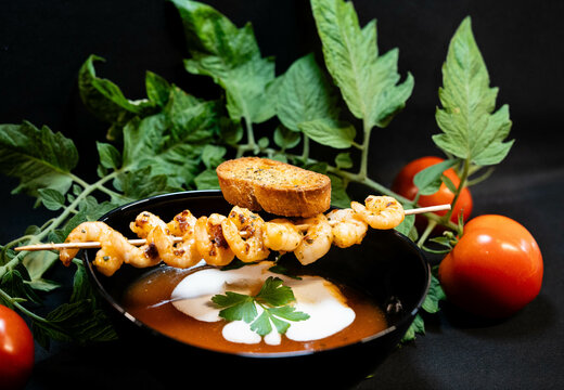 Assorted plate of shrimp skewer above bowl of soup