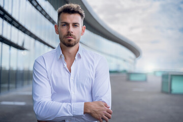 Caucasian male in white formal button shirt standing with folded arms