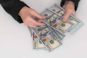 Woman hands counting a pile of 100 US dollar banknotes