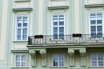 Soft Green and Yellow Facade with Ornate Balcony and Windows on Historic European Building with...