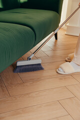 Dry cleaning the floor under furniture with a long-handled brush