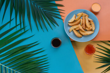 French fries and dipping sauces on a tropical colorful background