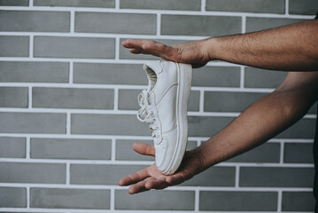 Man Holding White Sneaker in Hand