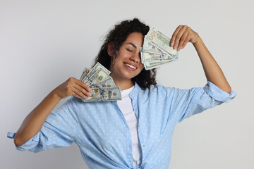Happy woman with dollar banknotes on light grey background
