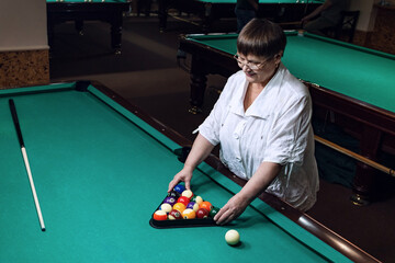 Fototapeta premium Grandma plays billiards in a billiard club.