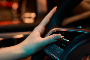 An up close image of a hand precisely adjusting a control in a luxurious automobile interior