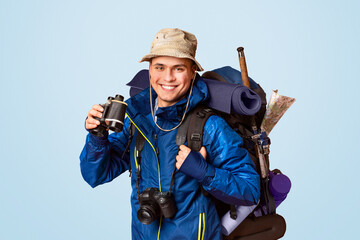 Hiker with binoculars smiling over orange studio background, panorama