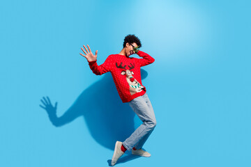 Full length photo of handsome young guy cheerful carefree dance dressed red christmas sweater celebrate winter holidays on blue background