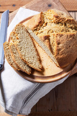 Homemade Irish soda bread cut into pieces and knife on wooden background.