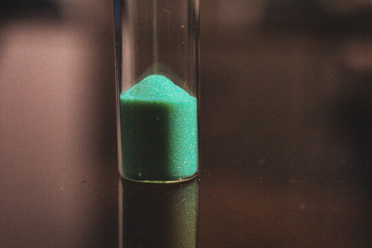 A vivid green hourglass, sand moving smoothly as it brings life to time.