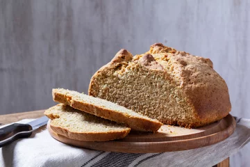 Gordijnen Homemade Irish soda bread cut into pieces and knife on wooden background. © Janna