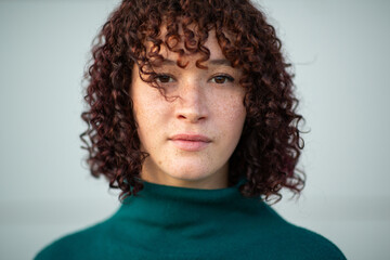 Woman with curly hair and freckles wearing green sweater