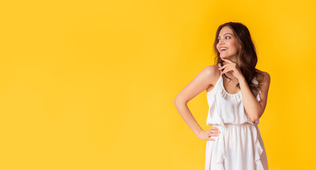 Excited beautiful lady in cocktail dress looking at copy space on colorful background, touching...