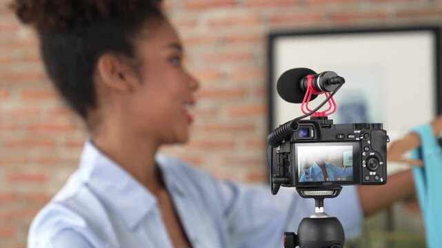 Rear view behide camera screen recording woman influencer shoot live stream vlog video review clothe crucial social media or blog. Girl with apparel studio lighting for marketing broadcasting online