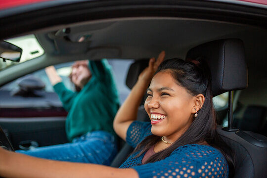 Two women laughing and celebrating while sitting in a red car