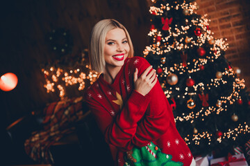 Photo of pretty young blonde female hugging self dressed christmas sweater tradition atmosphere decor house indoors room