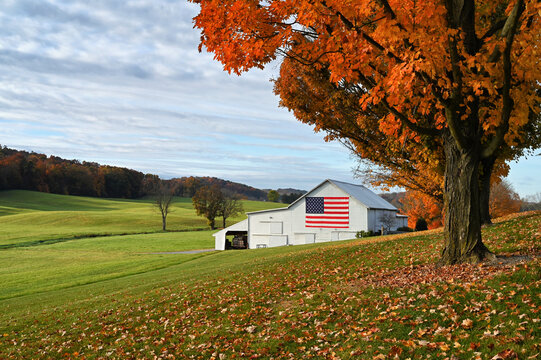 Barn in autumn landscape with large American USA flag