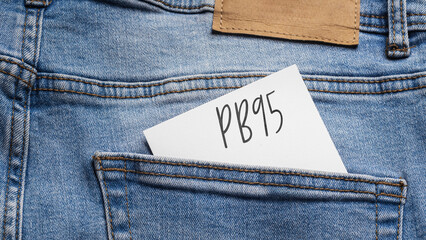 White card with a handwritten inscription "PB95", inserted into the pocket of blue pants jeasnow (selective focus)