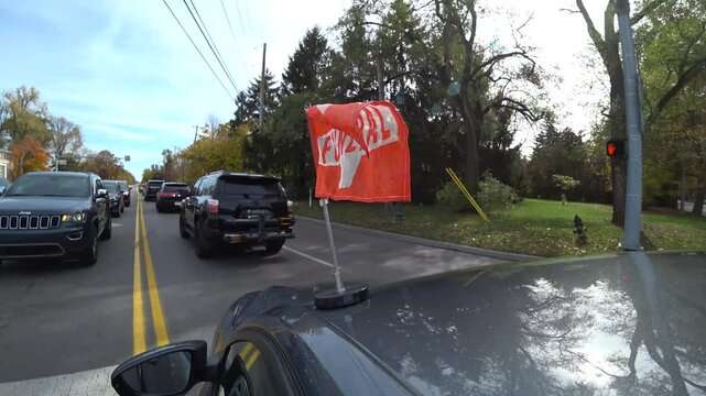 Orange funeral flag on car in procession turning corner