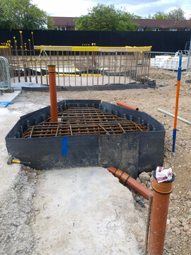 Reinforced pile cap with integrated drainage pipe on construction site for foundation support and water management.
