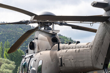 Black painted modern H225M military transport helicopter stationary on the ground