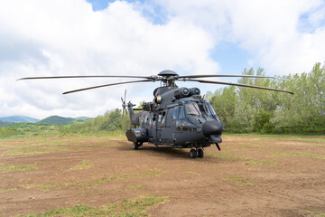 Black painted modern H225M military transport helicopter stationary on the ground