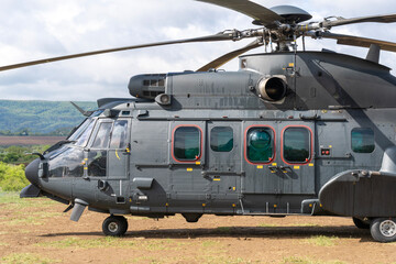 Black painted modern H225M military transport helicopter stationary on the ground