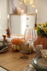 Stylish table setting with beautiful dishware, glasses and autumn decor in dining room