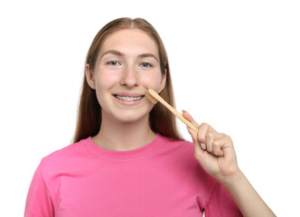 Smiling girl with braces cleaning teeth on white background