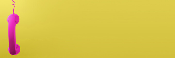 Magenta color telephone handset on yellow background. Banner design with space for text