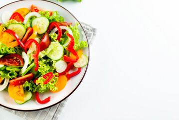 vegetable salad of fresh tomatoes, cucumbers, onions, lettuce on white plate.