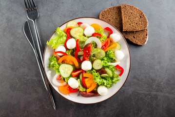 salad with red and yellow tomatoes, peper, cucumbers, lettuce and mozzarella.