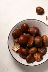 Delicious edible chestnuts in a small bowl on a white table