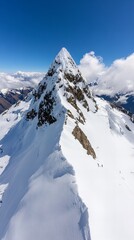 Fototapeta premium Aerial view of a snow-capped mountain peak with hikers on the ridge.