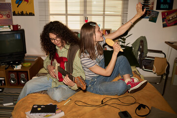 Two friends sharing musical moments in lively bedroom with vintage decor, decorated with posters...