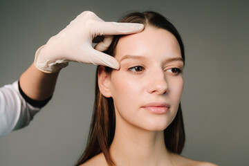 Naklejka premium Portrait of woman getting prepared for plastic surgery procedures. Correcting the shape of the forehead. Contour plastic treatment for beautiful shape of the face.