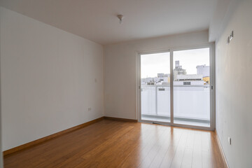 habitacion vacía de departamento con ventana , acabados modenos piso de melamina, y paredes color blanco