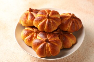 Tasty pumpkin shaped buns on beige textured table, closeup