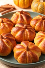 Tasty pumpkin shaped buns on beige table, closeup