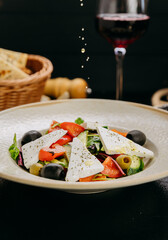 Mediterranean salad with feta, olives and vegetables, served with wine and flatbread in cozy setting