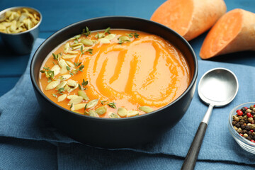Delicious sweet potato soup with pumpkin seeds served on blue wooden table, closeup