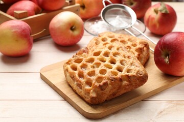 Delicious puff pastries with apples on white wooden table, closeup