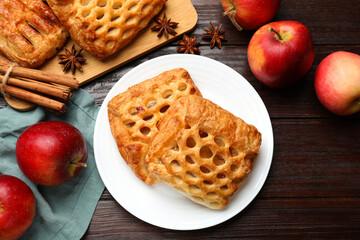 Delicious puff pastries, apples, cinnamon and anise stars on wooden table, top view